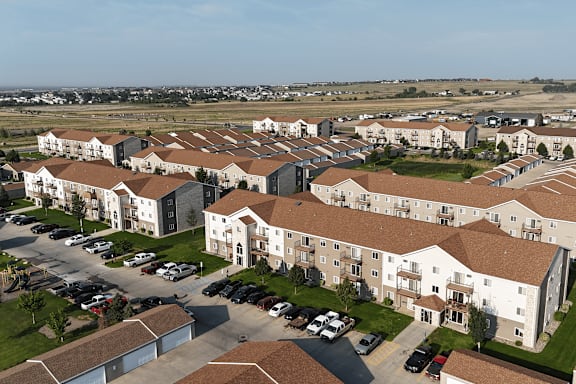 A large apartment complex with a parking lot in front.