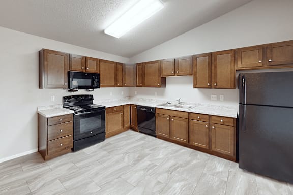 A kitchen with wooden cabinets and black appliances.