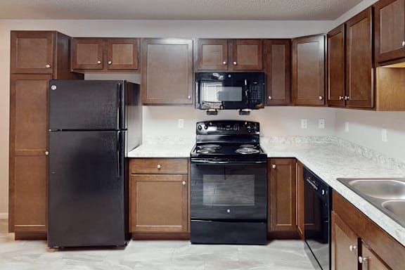 A kitchen with black appliances and wooden cabinets.