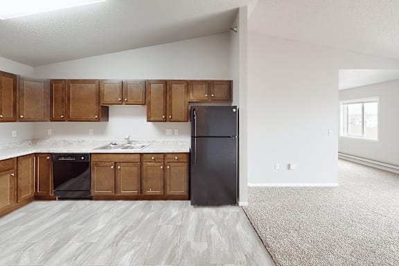 A kitchen with wooden cabinets and a black fridge.