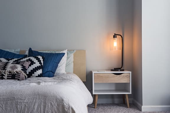 a bedroom with a bed with blue and white bedding and a white nightstand with a