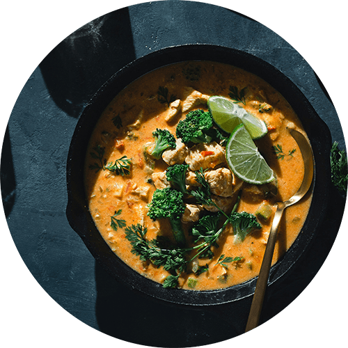 A bowl of creamy soup with broccoli and lime garnish.