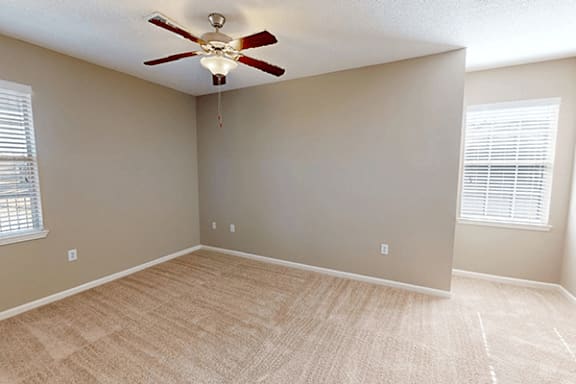an empty living room with a ceiling fan