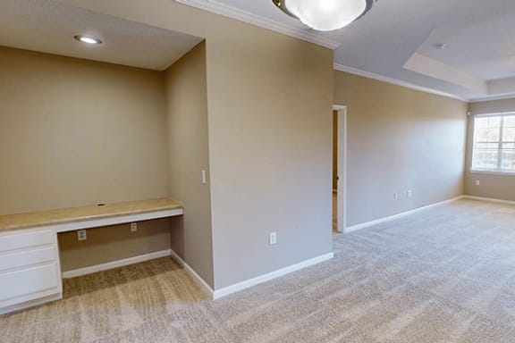 an empty living room and dining room with a desk