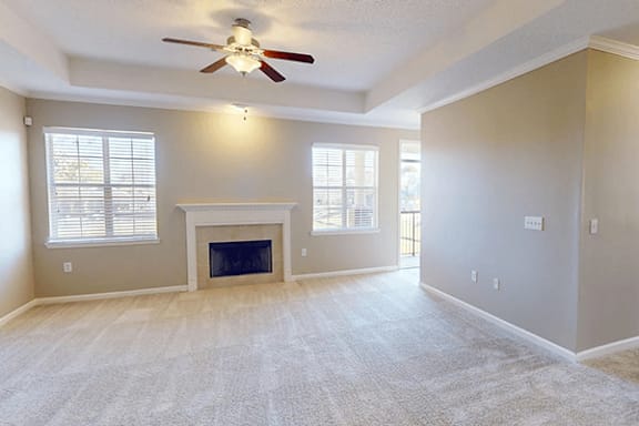 an empty living room with a fireplace and a ceiling fan