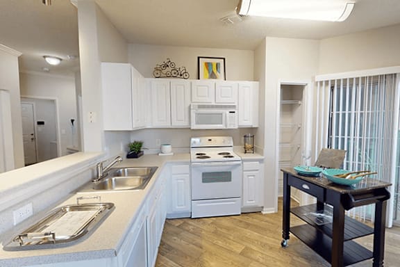 a kitchen with white cabinets and a sink and a stove