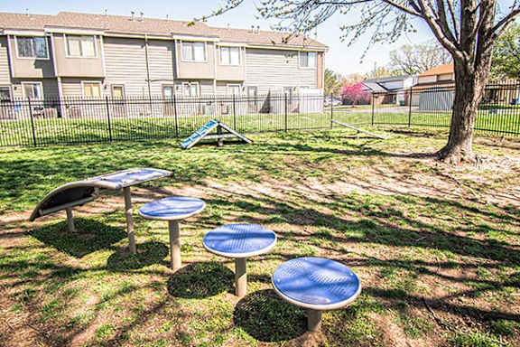 A playground with blue slides and tables in a grassy area.