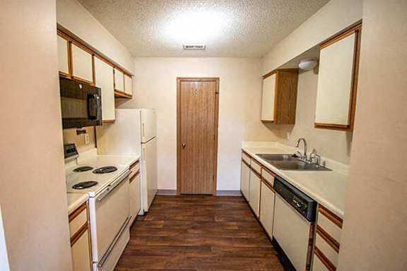 A kitchen with white appliances and wooden cabinets.