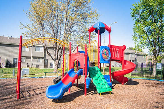 A playground with a red and blue slide and a yellow arch.