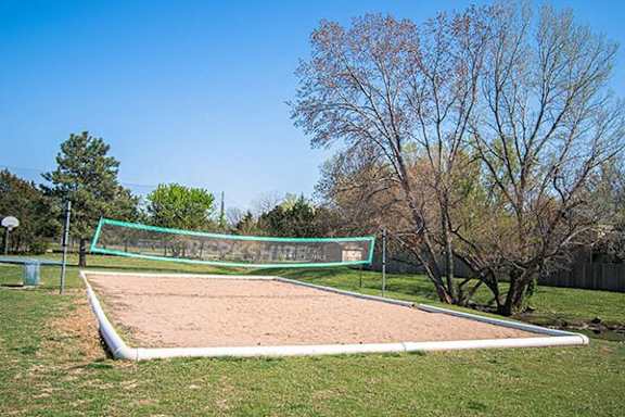 A sand volleyball court with a green net and white posts.