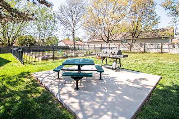 A picnic table with a green top is surrounded by a black fence.