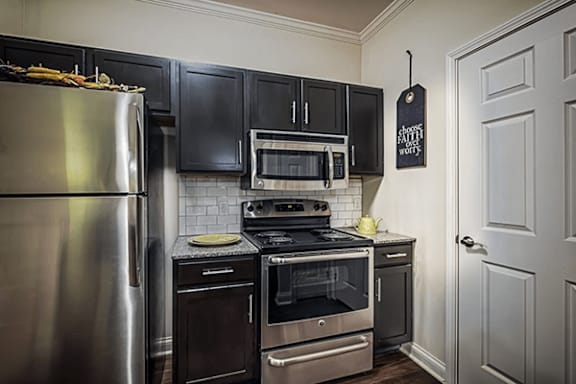 A kitchen with a stainless steel refrigerator and black cabinets.