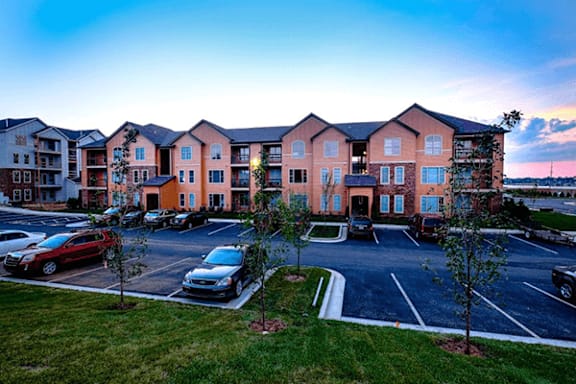 A parking lot in front of a large apartment building.
