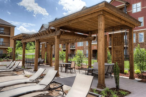 A wooden pavilion with loungers and a slide in the foreground.