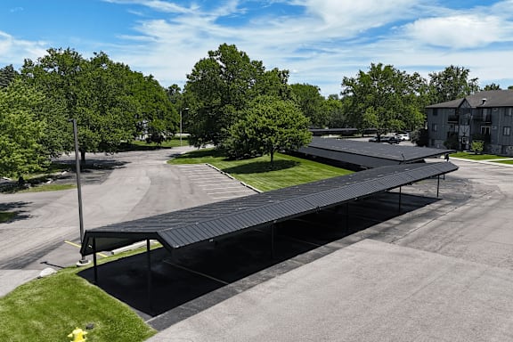 A black covered walkway leads from a parking lot to a building.