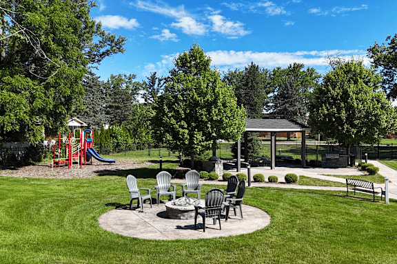 A park with a playground, picnic table, and benches.