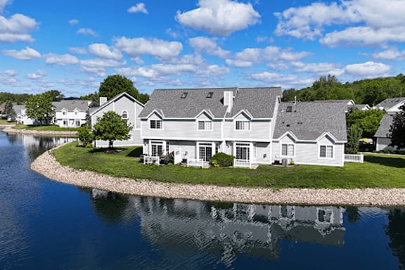 A house with a grey roof is surrounded by water.