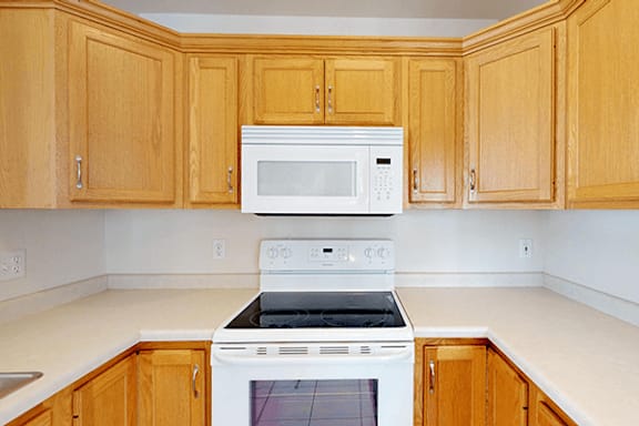 A white oven and microwave in a kitchen with wooden cabinets.