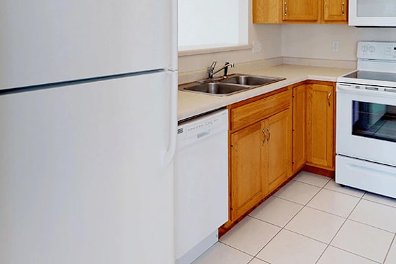 A white refrigerator is in a kitchen with wooden cabinets.