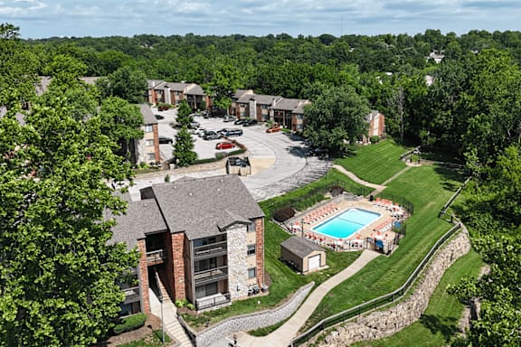 A bird's eye view of a resort with a swimming pool surrounded by trees.