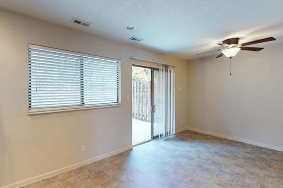 A room with a ceiling fan and sliding glass doors.