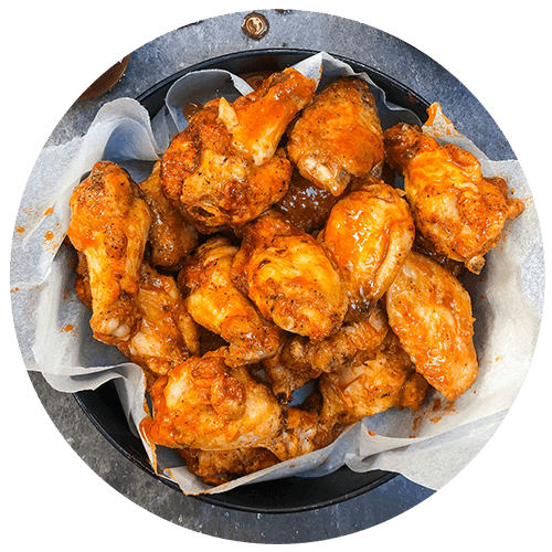A plate of fried chicken wings and two red chili peppers.
