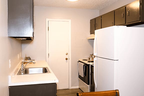 A kitchen with a sink, stove, and refrigerator.