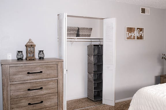 A white closet with a hanging shelf and a basket on top.