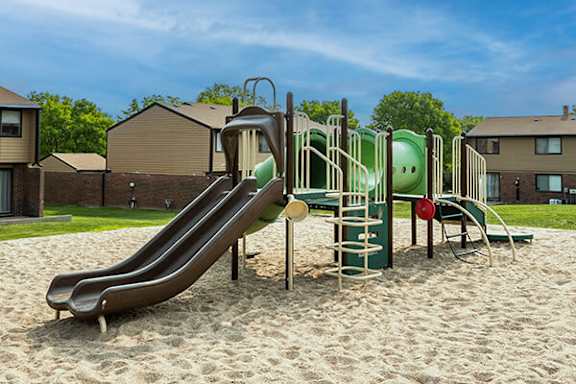 A playground with a green slide and a red ball.