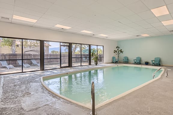 a large indoor swimming pool with patio furniture