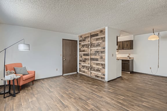 A room with a wooden floor and a chair with a pillow on it.