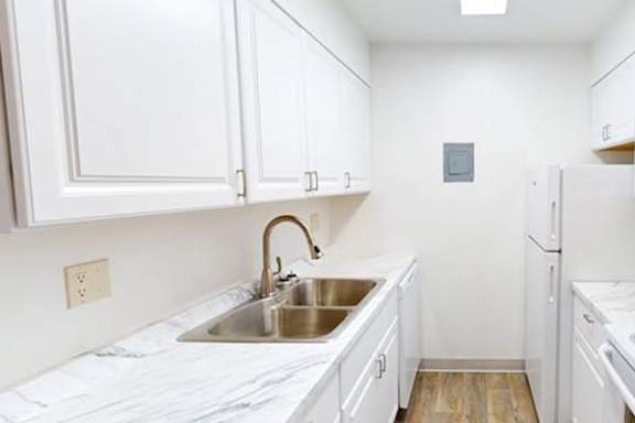 A kitchen with white cabinets and a marble countertop.
