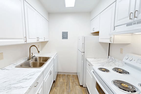 A white kitchen with a stove, sink, and refrigerator.