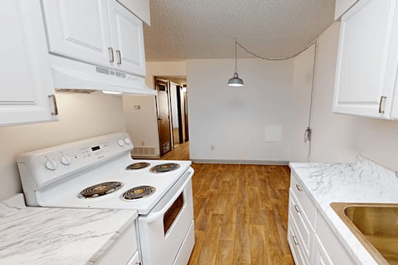 A kitchen with a white stove and wooden floors.