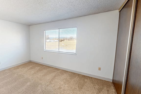 A room with a window and a carpeted floor.