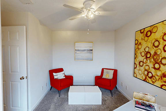 a living room with red chairs and a ceiling fan