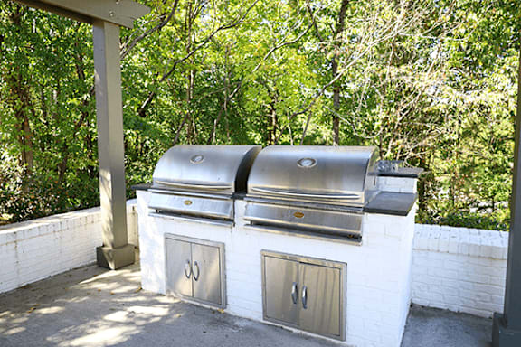 a barbecue grill on a patio with trees in the background