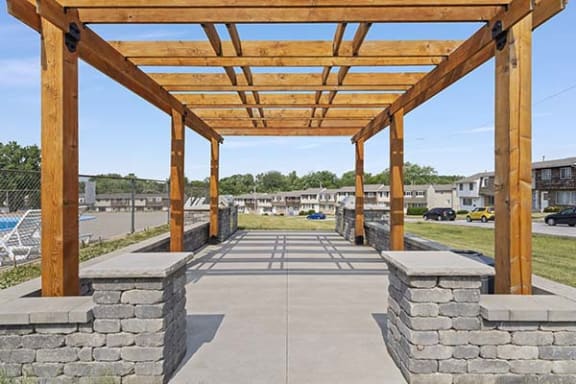 a covered area with stone pillars and a wood roof