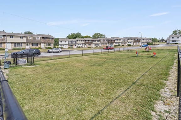 a yard with a fence and cars on the road