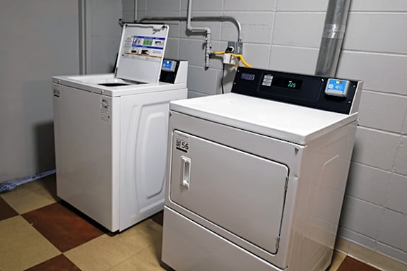 Two large industrial washing machines in a laundry room.