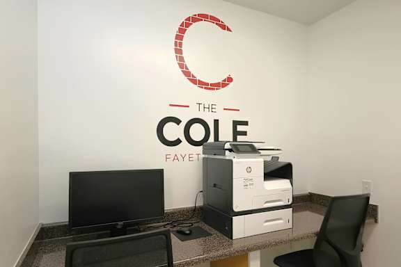 A white wall with a red C logo and the words "The Cole Fayet" written on it.