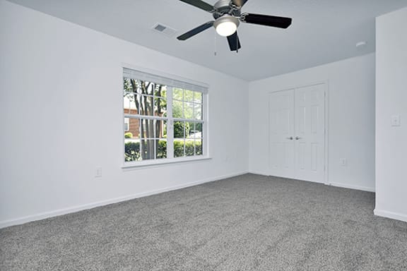 A room with a ceiling fan and carpeted floor.