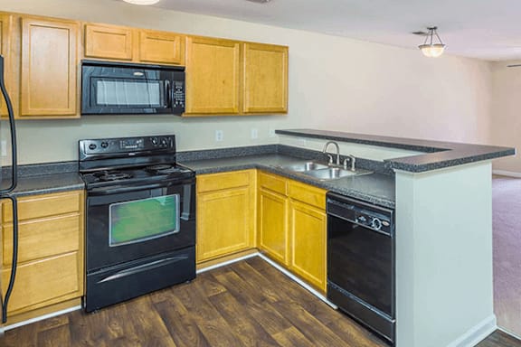 A kitchen with black appliances and wooden cabinets.