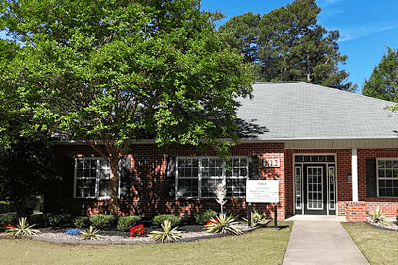 A small brick building with a sign that says "Office" in front of it.