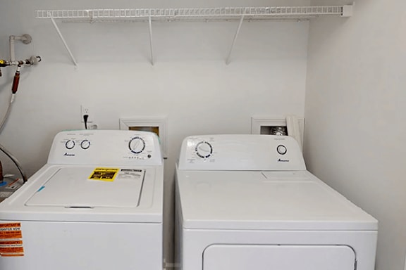 Two white front loading washing machines in a laundry room.