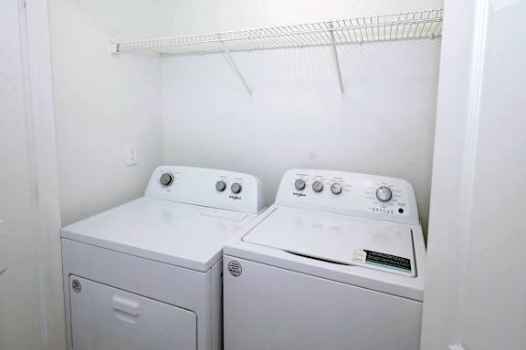 Two white front loading washing machines in a small laundry room.