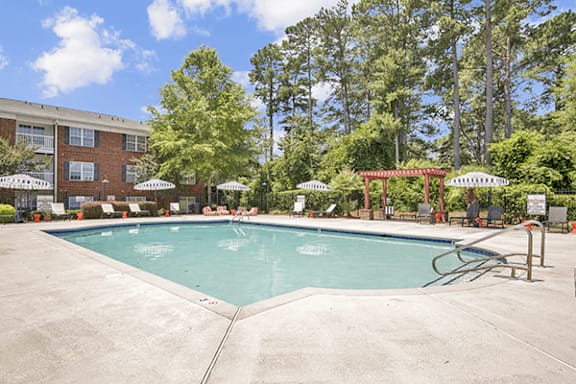 A large swimming pool surrounded by trees and a building.