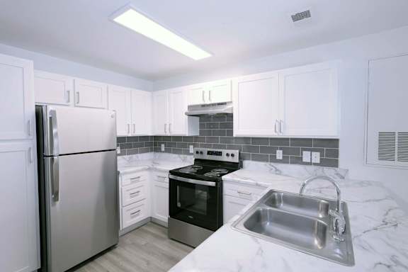 A kitchen with white cabinets and a marble countertop.