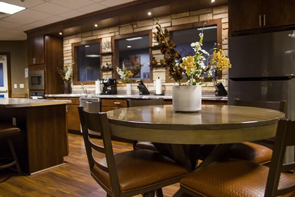 a kitchen with a round table with a vase of flowers on top of it