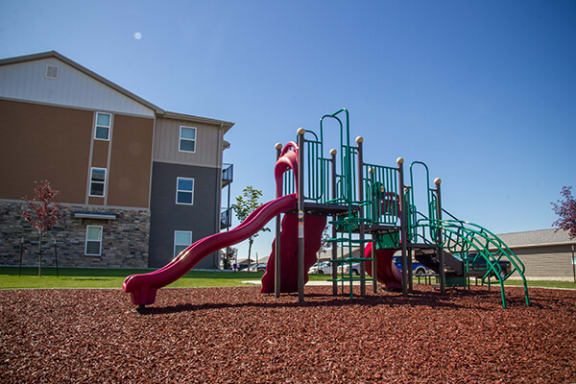 a playground with a slide in front of an apartment building